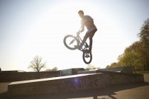 Young man, in mid air, doing stunt on bmx at skatepark — Stock Photo