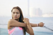Young woman exercising arms and shoulder on waterfront, Hong Kong — Stock Photo