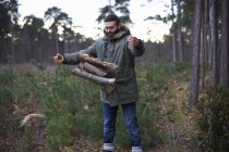 Junger Mann wirft Baumstämme für Lagerfeuer in Wald — Stockfoto
