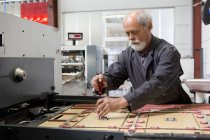 Engineer repairing manufacturing machine in cardboard factory — Stock Photo