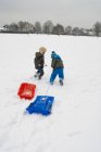 Garçons dans la neige avec traîneaux — Photo de stock