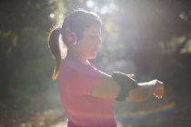 Seitenansicht einer reifen Frau, die Kopfhörer trägt und eine Armbinde vorbereitet — Stockfoto