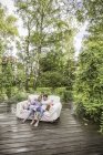 Vue grand angle du couple assis sur un canapé vintage dans le jardin et utilisant une tablette numérique — Photo de stock