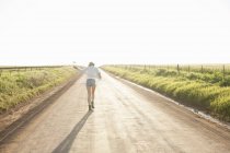 Mulher adulta média andando estrada rural, visão traseira — Fotografia de Stock