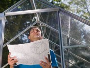 Man with greenhouse plans in garden — Stock Photo