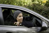 Молодая женщина наклоняется и смотрит из окна машины — стоковое фото