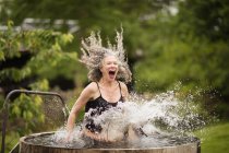 Mature woman splashing into fresh cold water tub at eco retreat — Stock Photo