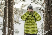 Man taking photo in snow covered forest, Russia — Stock Photo
