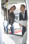 Cliente e vendedor verificando a altura interior do veículo na concessionária de automóveis — Fotografia de Stock