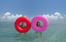 Casal olhando através de anéis infláveis no mar — Fotografia de Stock