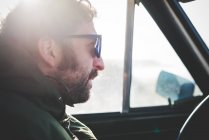Крупним планом середнього дорослого чоловіка в сонцезахисних окулярах в сонячній машині — стокове фото