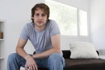 Portrait of serious young man on living room sofa — Stock Photo