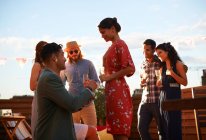 Man proposing to woman on roof terrace, sunset in background — Stock Photo