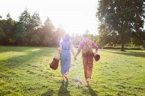 Vue arrière d'un jeune couple romantique portant un tapis dans un parc — Photo de stock