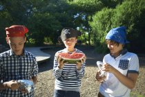 Drei kleine Jungen beim Mittagessen mit Wassermelone im Park — Stockfoto