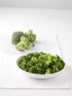 Raw broccoli on marble cutting board and bowl — Stock Photo