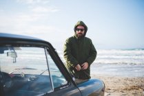Mid adult man with vintage car fastening anorak on beach, Sorso, Sassari, Sardinia, Italy — Stock Photo
