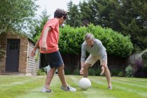 Дедушка и внук играют в футбол в саду — стоковое фото
