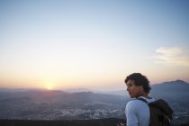 Joven mirando hacia el paisaje y la puesta de sol, Javea, España - foto de stock