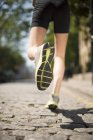 Läufer joggt auf Kopfsteinpflaster — Stockfoto