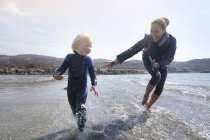 Madre e hijo corriendo en la playa, Loch Eishort, Isla de Skye, Hébridas, Escocia - foto de stock