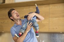 Мужчина играет с малышом сыном на кухне — стоковое фото