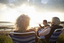 Члени сім'ї відпочивають на пляжі на заході сонця — стокове фото