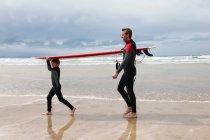 Père et Fils portant une planche de surf — Photo de stock