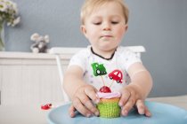 Baby boy playing with cupcake — Stock Photo
