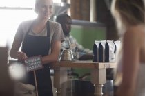 Junge Kellnerin berät über Kaffeewahl im Café — Stockfoto
