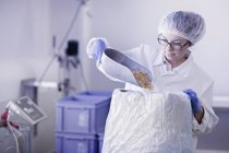 Ouvrier d'usine ramassant de la nourriture dans le sac — Photo de stock