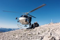Equipo de salto BASE saliendo de helicóptero en la cima de la montaña, Alpes italianos, Alleghe, Belluno, Italia - foto de stock