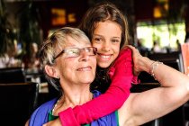 Portrait of girl with arms around grandmother — Stock Photo