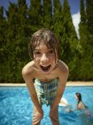 Retrato de niño inclinado hacia delante frente a la piscina, Mallorca, España - foto de stock