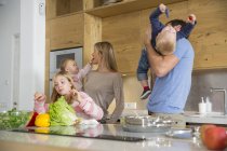 Fille avec la famille préparant des légumes sur le comptoir de cuisine — Photo de stock