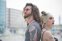 Portrait of punk hippy couple back to back on city street — Stock Photo