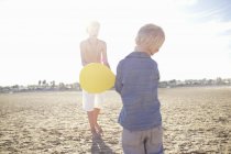 Masculino criança e irmão jogando morcego e bola na praia — Fotografia de Stock