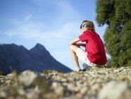 Niño sentado y mirando a las montañas, Mallorca, España - foto de stock