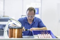 Male worker assembling electromagnetic coils in electronics factory — Stock Photo