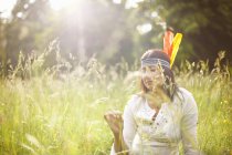 Mature woman in native american headdress in long grass — Stock Photo