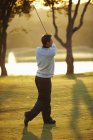 Гравець у гольф у sunlight проведення гольф-клуб, приймаючи гольф свінг, хтось дивитися вбік — стокове фото
