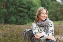 Mulher adulta média usando suéter no banco — Fotografia de Stock