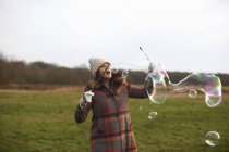 Donna in campo con bacchette di bolla per fare bolle — Foto stock