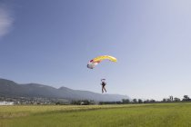 Female skydiver parachuting into field, approaching the landing zone, Grenchen, Berne, Switzerland — Stock Photo