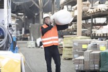 Молодий чоловічий складський робітник, що носить рулон пінополістиролу на плечі — стокове фото