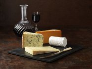Selection of cheese on board with red wine — Stock Photo