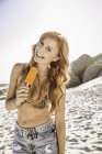 Retrato de mulher com cabelos longos e ruivos comendo gelado na praia, Cidade Do Cabo, África do Sul — Fotografia de Stock