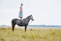 Mujer en falda de pie sobre el caballo gris manzana en el campo - foto de stock