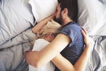 Couple lying in bed together, sleeping, arms around each other — Stock Photo