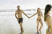 Casal adulto médio usando biquíni e calções de banho de mãos dadas na praia, Cidade do Cabo, África do Sul — Fotografia de Stock
